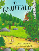 An illustrated mouse walks upright along a yellow path near a meadow and woods as the mysterious Gruffalo peeks behind a bush.