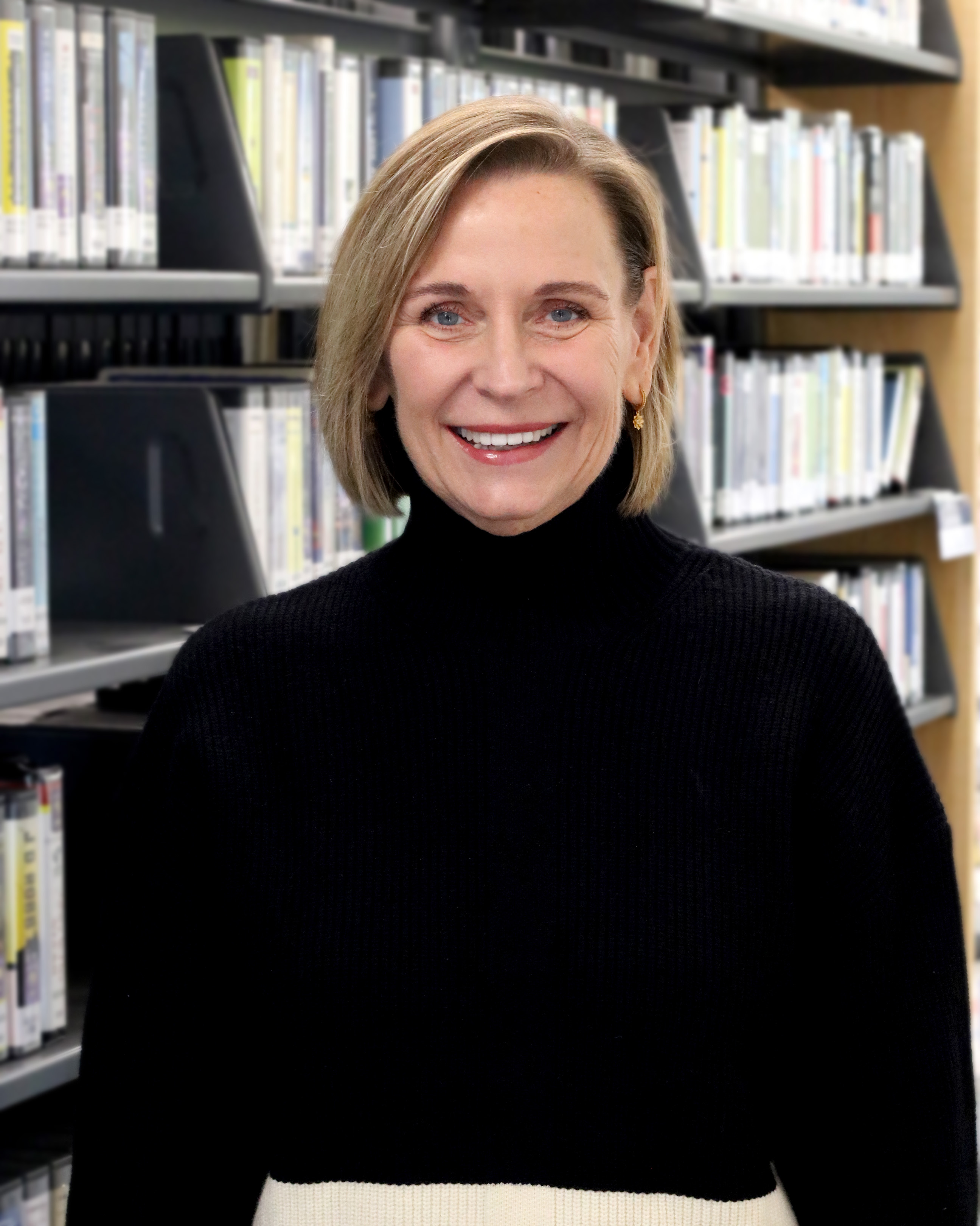 Library Director Pam leffler stands in front of book shelves
