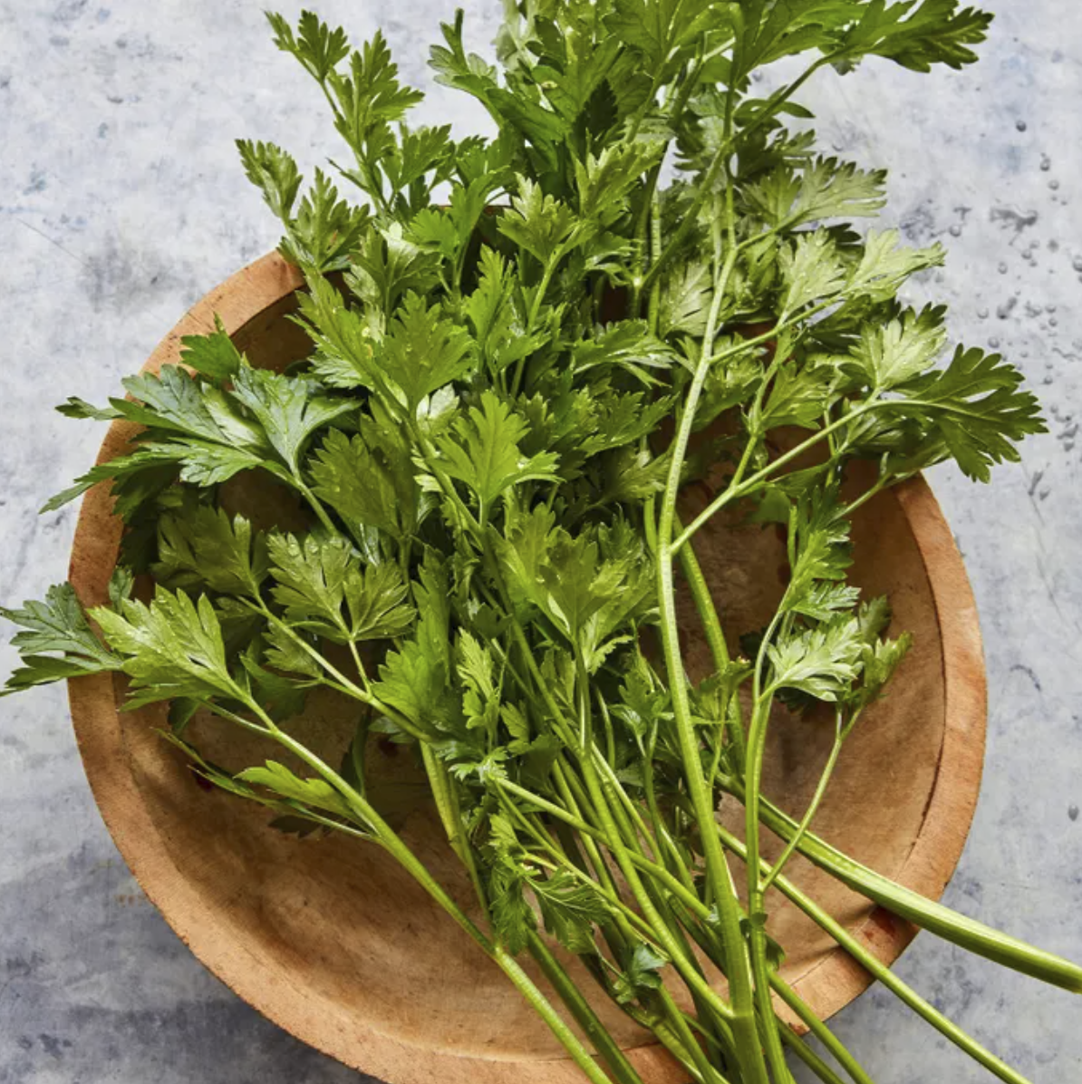 stems of leafy italian parsley on a wooded bowl