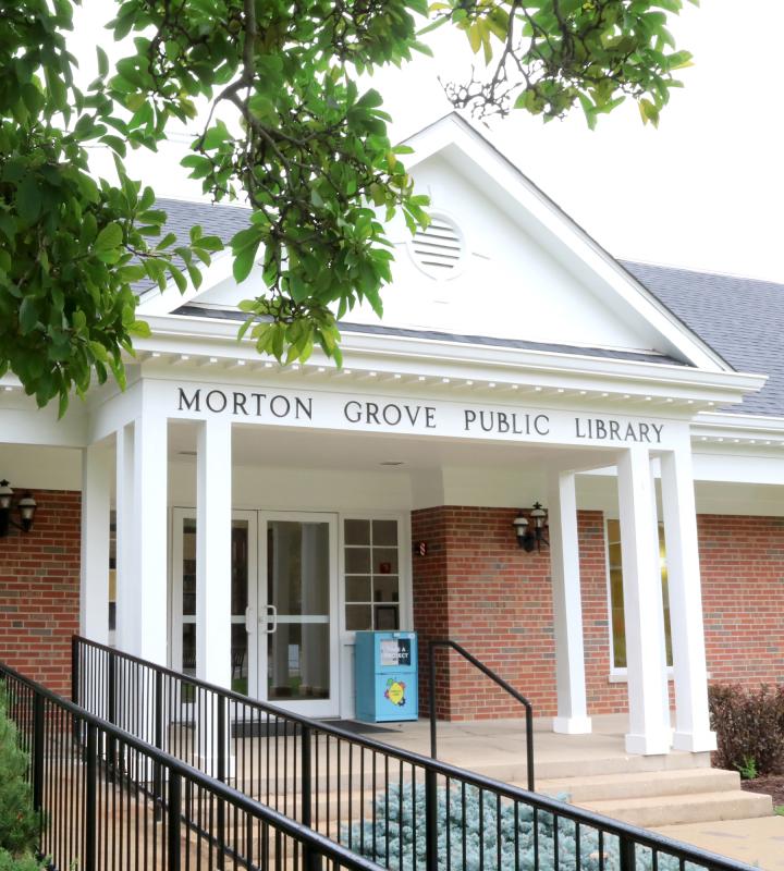 the front of the morton grove public library building. white columns, concrete steps, and red brick walls